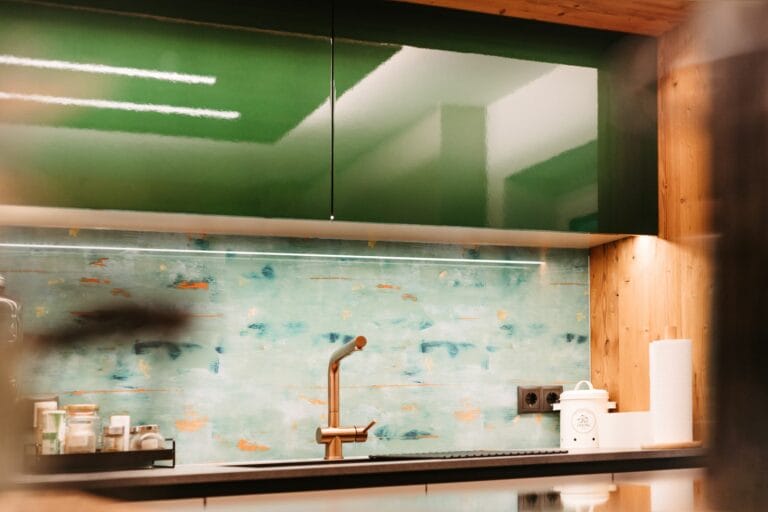 Küchenzeile mit grünen Lackfronten und bedruckter Glasrückwand