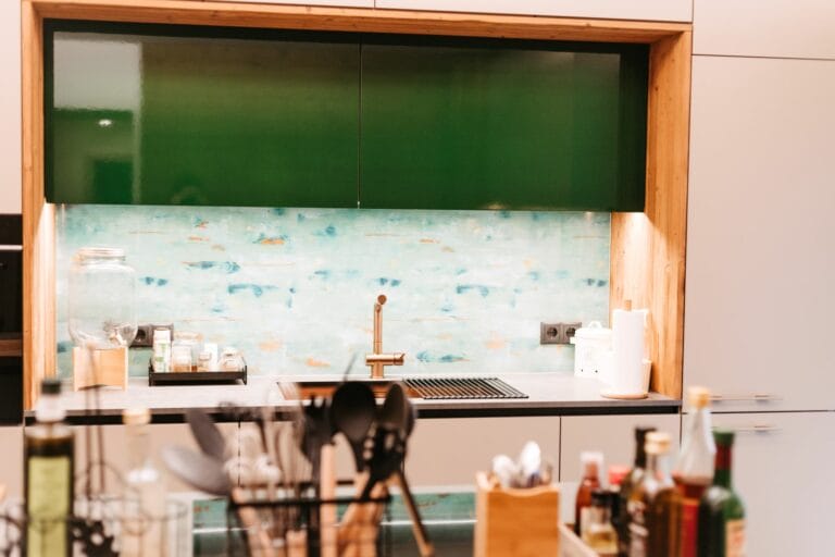 Küchenzeile mit grünen Lackfronten und bedruckter Glasrückwand