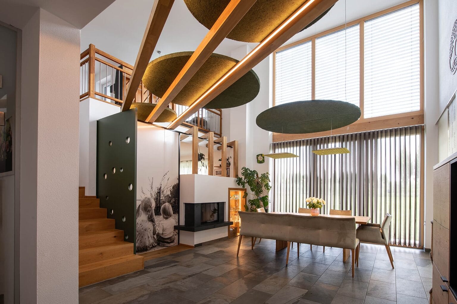 Kreative Raumtrennung und Akustiklösung von Horst Steiner Innenarchitektur für Wohn-/Esszimmer mit Galerie.