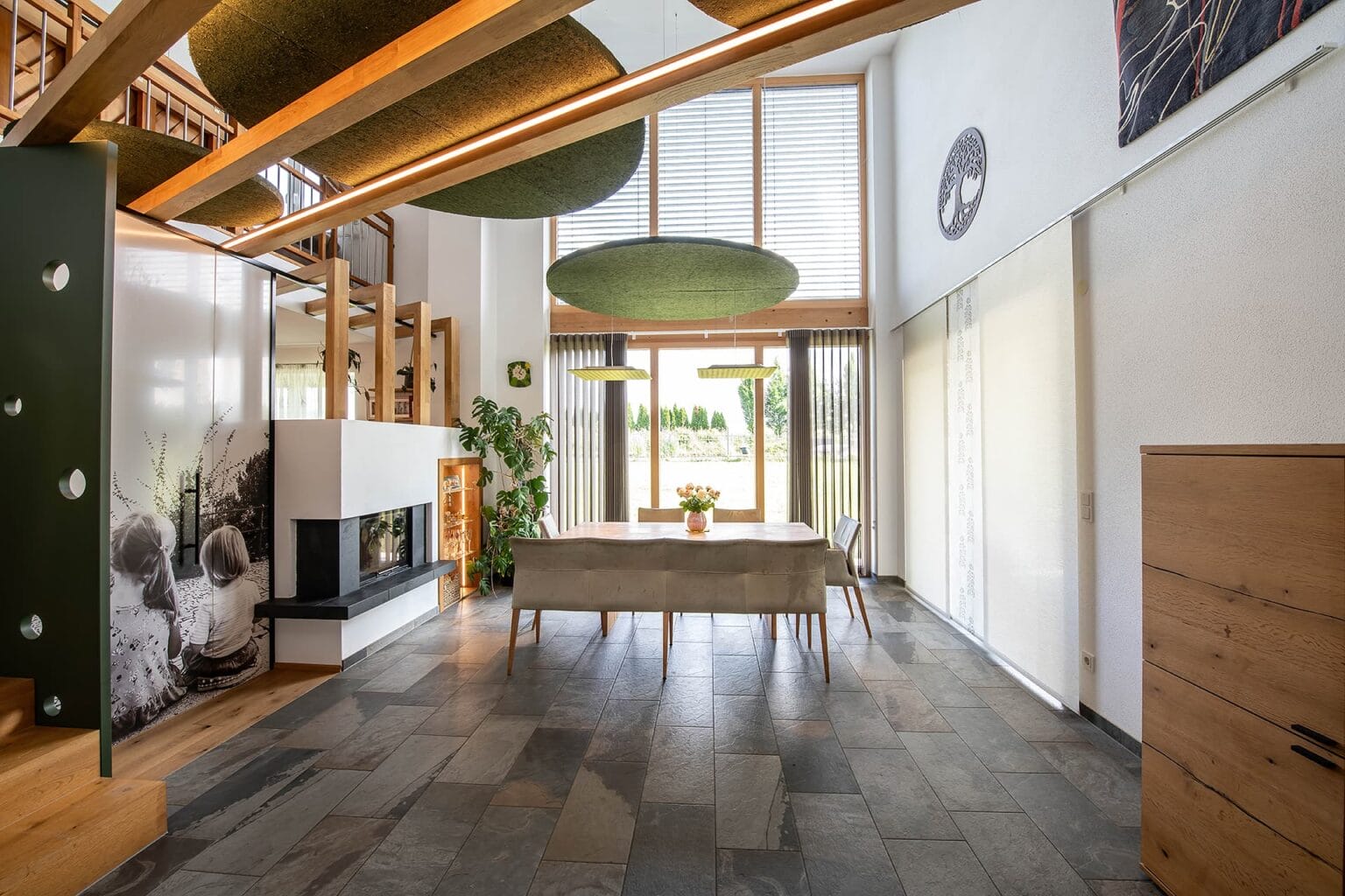 Raumtrennung zwischen Ess- und Wohnzimmer kreativ gelöst mit Glaswand. Holzbalken mit Filzplatten zur Schalldämmung.